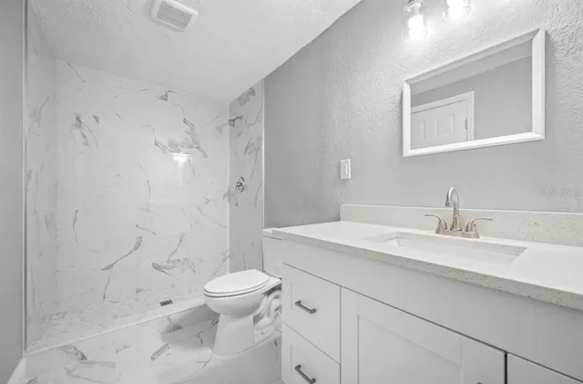 a bathroom with a sink a toilet and shower