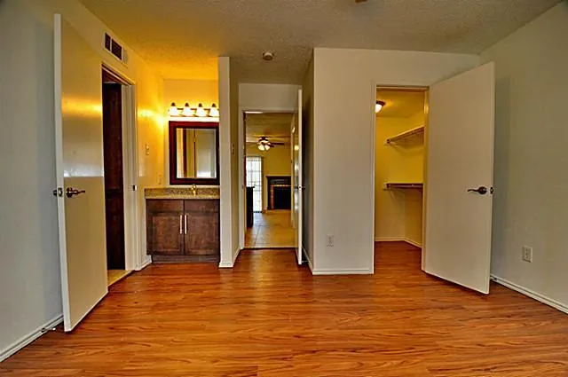 a view of a hallway with wooden floor and a bathroom