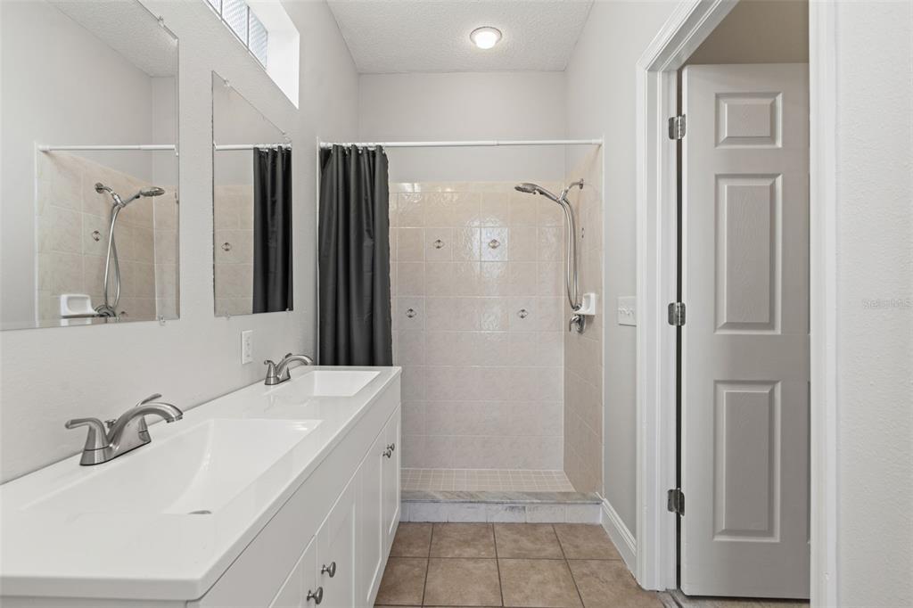 8433 Beachwood Court Spring Hill, FL 34606 - Photo 14 of 38 a bathroom with a double vanity sink a mirror a shower and a bathtub
