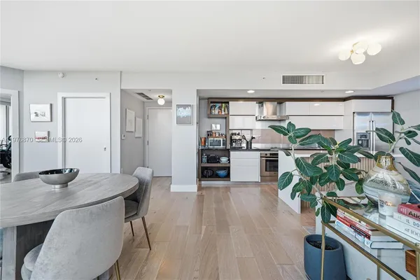 a kitchen with stainless steel appliances a dining table chairs stove and cabinets