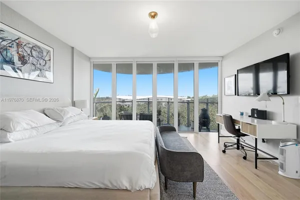 a bedroom with a bed a chair and potted plant on the dresser
