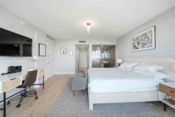 a spacious bedroom with a bed and a flat screen tv