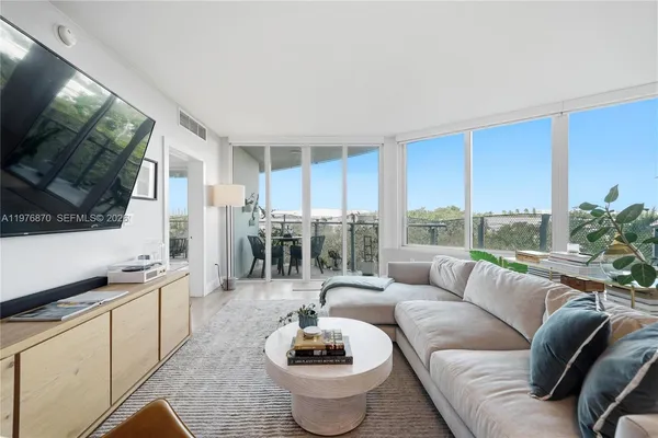 a living room with furniture a flat screen tv and a floor to ceiling window