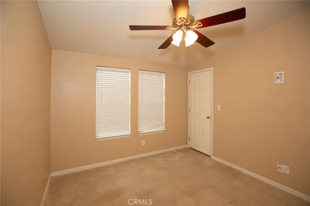 an empty room with closet and a chandelier fan