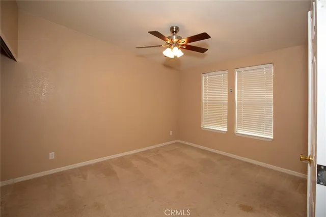 an empty room with a chandelier fan and windows