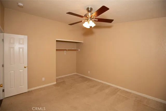 an empty room with closet and a chandelier fan