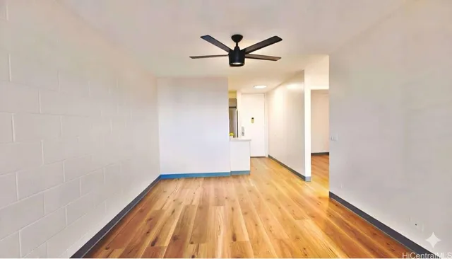 a view of empty room with wooden floor and fan