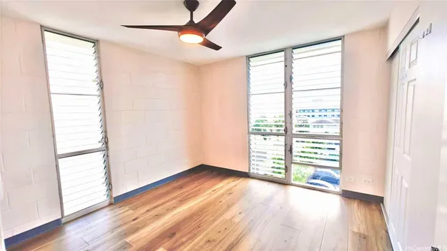 an empty room with wooden floor and windows with curtains