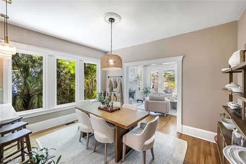 a view of a dining room and livingroom with furniture wooden floor kitchen view and a chandelier