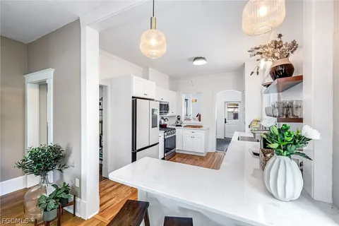 a kitchen with stainless steel appliances granite countertop a sink stove oven and white cabinets with wooden floor