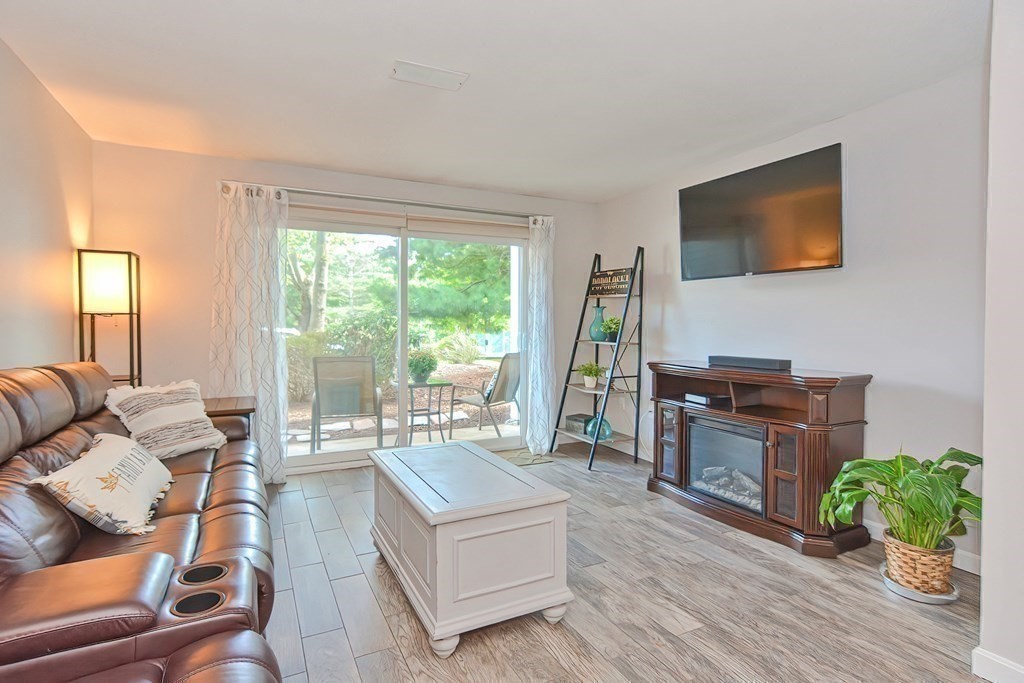 801 Franklin Crossing Road, Unit 801 Franklin, MA 02038 - Photo 12 of 38 a living room with furniture a flat screen tv and a floor to ceiling window
