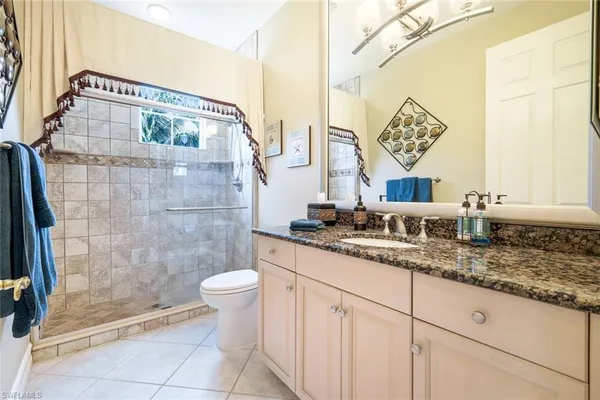 a bathroom with a granite countertop sink a toilet a mirror and shower