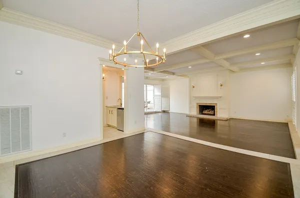 a view of empty room with wooden floor and kitchen