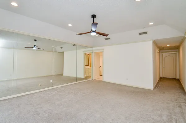 a view of an empty room and chandelier fan
