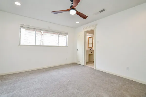 an empty room with chandelier fan and windows