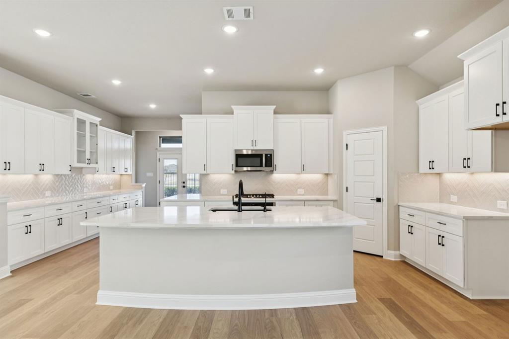 1366 Chisos Way Forney, TX 75126 - Photo 10 of 38 a large kitchen with stainless steel appliances a large counter top a stove a sink dishwasher and a refrigerator