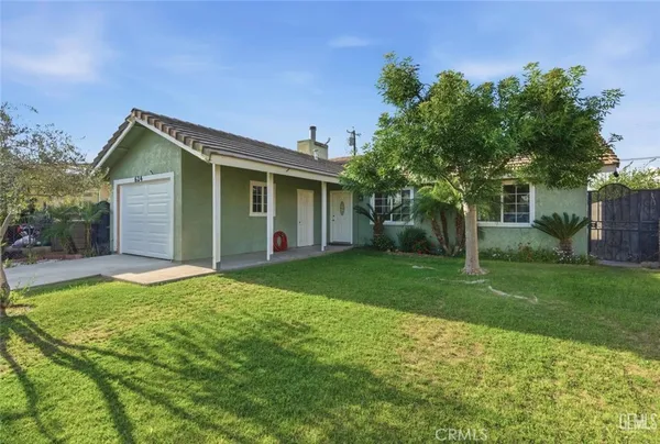 a backyard of a house with potted plants and large tree