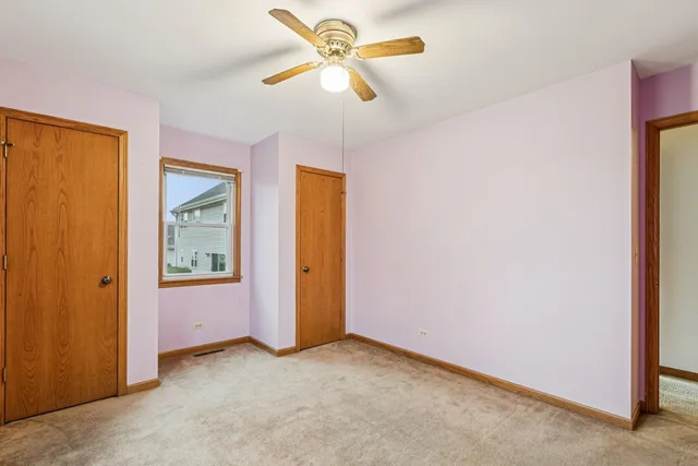 an empty room with closet and a ceiling fan