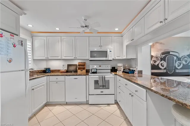 a kitchen with granite countertop white cabinets and white appliances