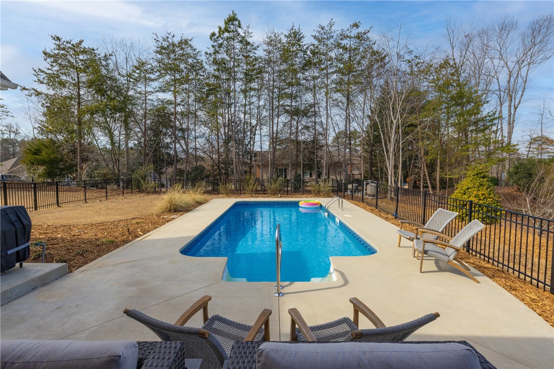 113 South Oak Pointe Drive Seneca, SC 29672 - Photo 35 of 50 Enjoy outdoor leisure with a private pool and spacious concrete patio, surrounded by natural landscaping.