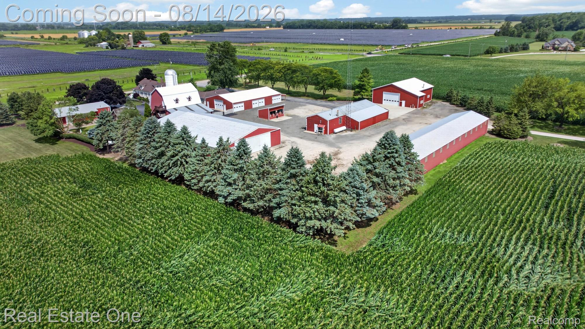 12139 Gooding Road Milan, MI 48160 - Photo 52 of 98 Expansive property with multiple red outbuildings, a prominent red barn with a silo, and surrounding cultivated fields