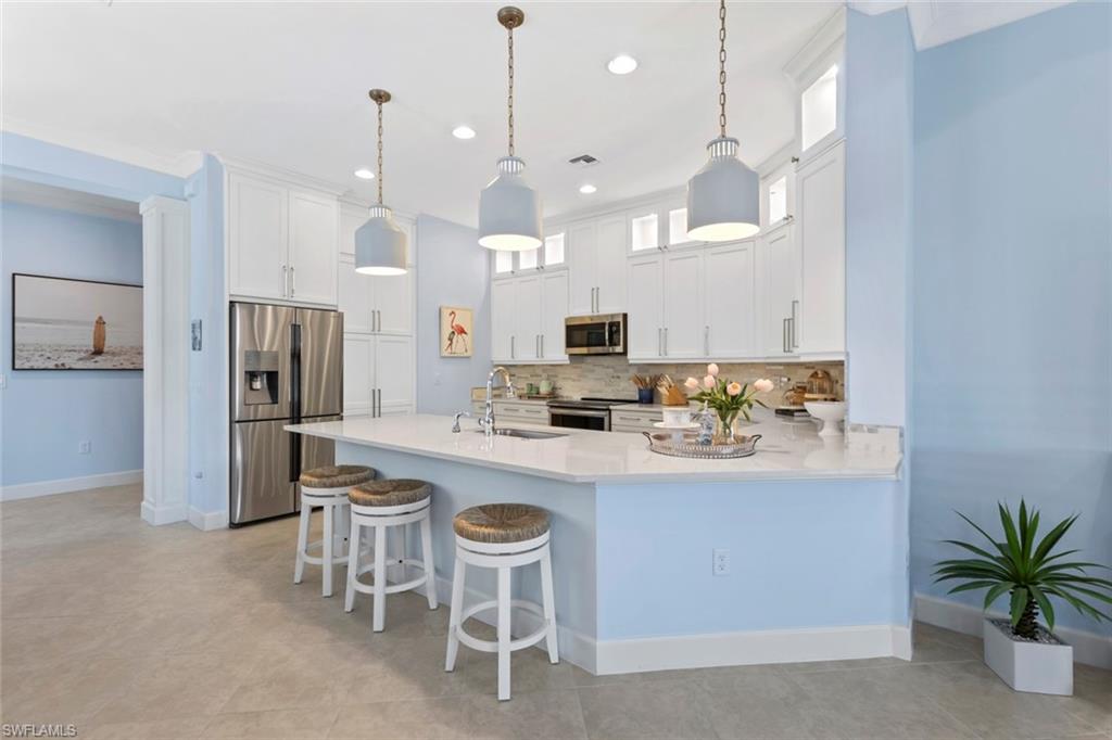 5690 Elbow Avenue Naples, FL 34113 - Photo 6 of 39 a kitchen with kitchen island granite countertop a sink a center island stainless steel appliances and cabinets