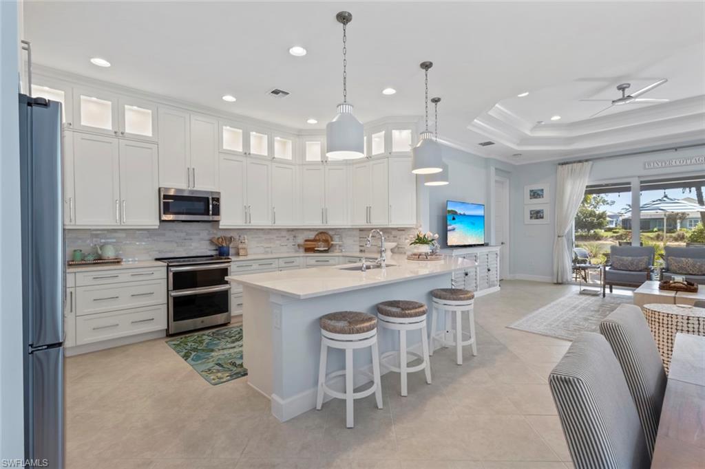 5690 Elbow Avenue Naples, FL 34113 - Photo 7 of 39 a large kitchen with kitchen island granite countertop lots of white cabinets appliances and furniture