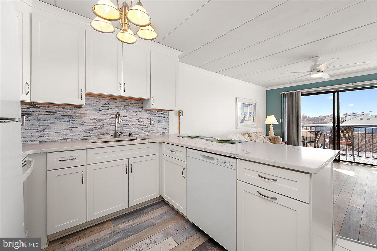 18 69th Street, Unit 9 Ocean City, MD 21842 - Photo 15 of 60 a kitchen with white cabinets and chandelier