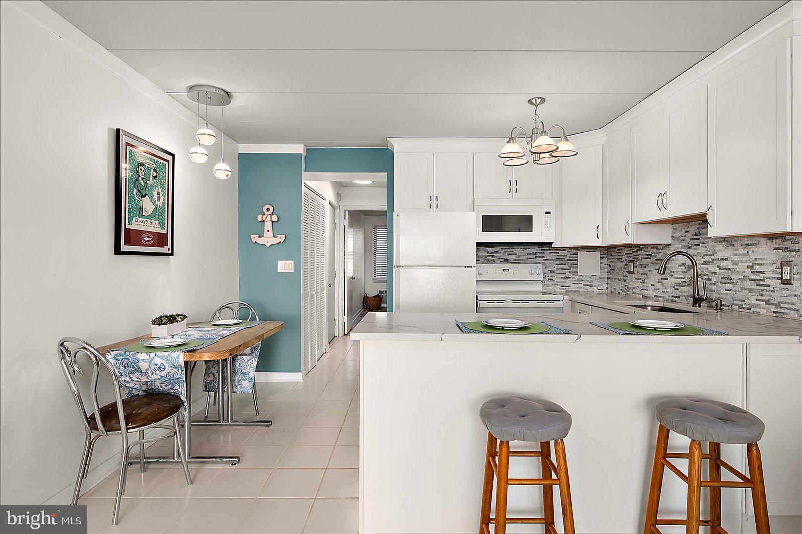 18 69th Street, Unit 9 Ocean City, MD 21842 - Photo 5 of 60 a kitchen with stainless steel appliances kitchen island a table chairs in it and white cabinets