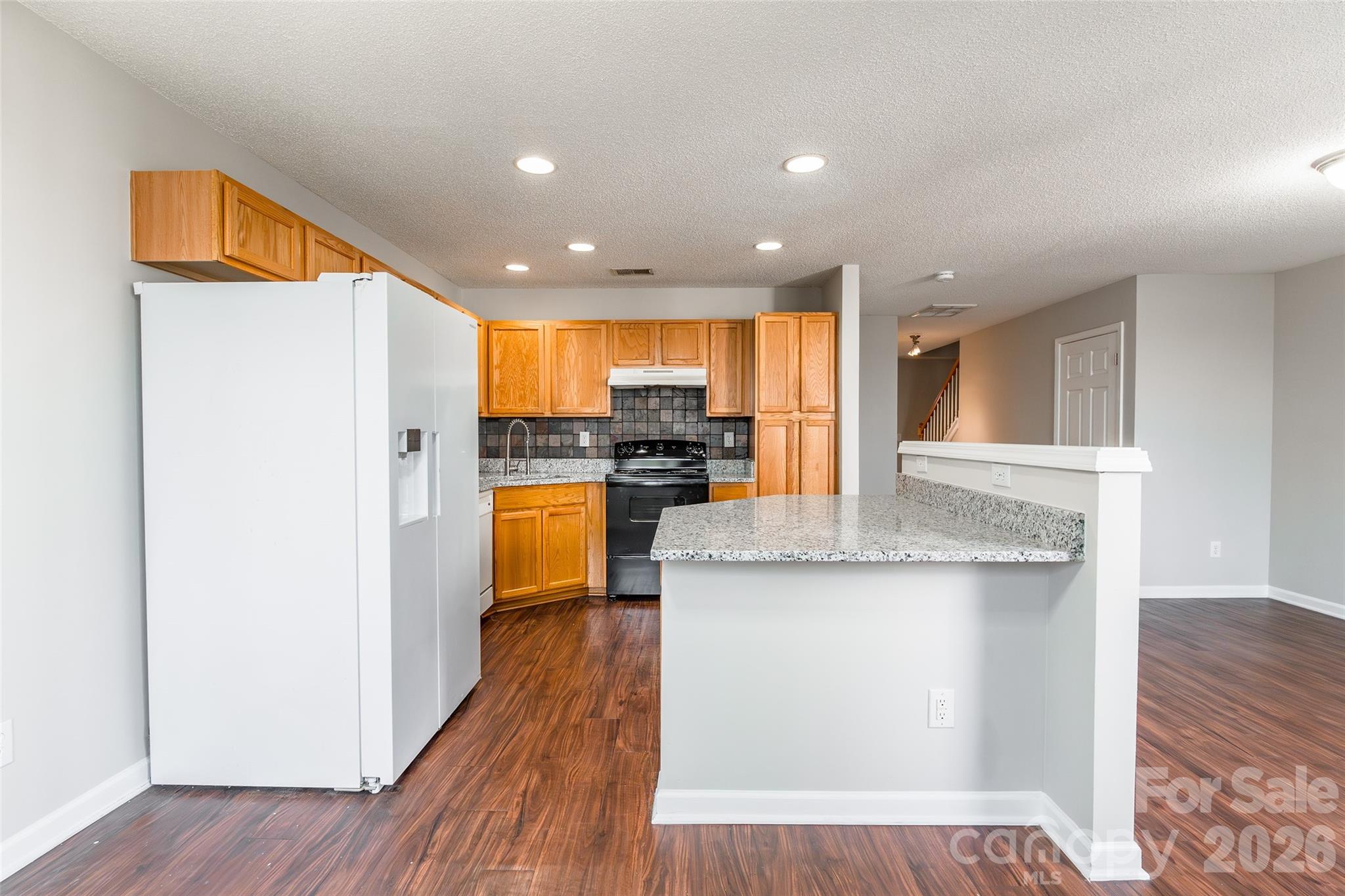 3167 Caldwell Ridge Parkway Charlotte, NC 28213 - Photo 12 of 36 a kitchen with stainless steel appliances granite countertop a refrigerator a stove and a wooden floors