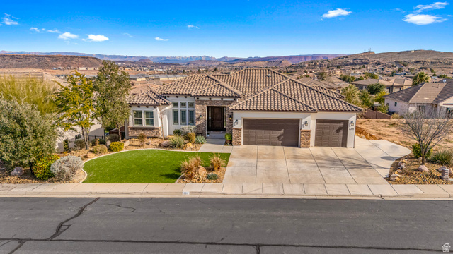 2311 South 1340 West St. George, UT 84770 - Photo 4 of 56 Mediterranean / spanish-style house with a garage, a front lawn, a mountain view, driveway, and stone siding
