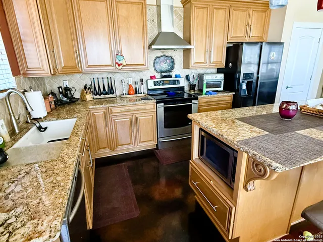 a kitchen with stainless steel appliances granite countertop a stove a sink and a refrigerator