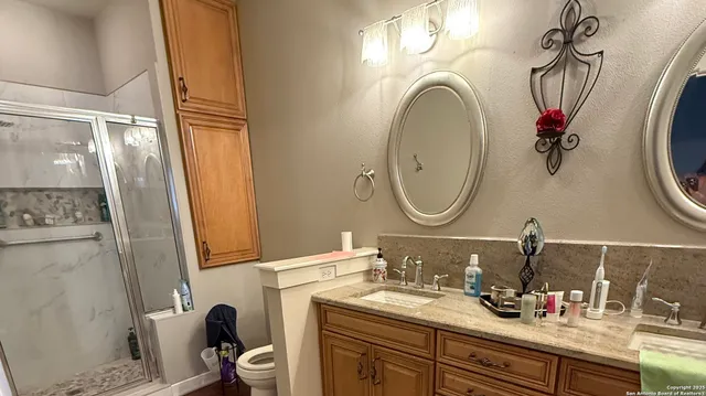 a bathroom with a granite countertop toilet sink and mirror