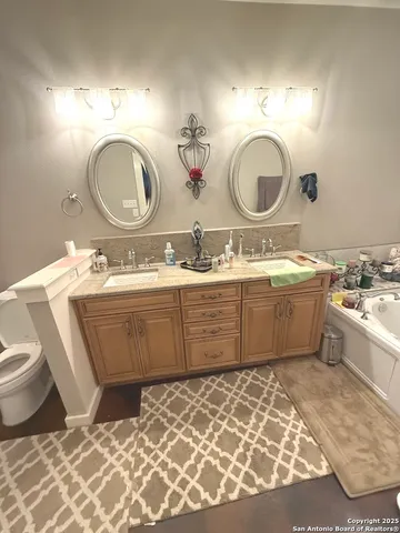 a bathroom with a double vanity sink mirror and bathtub