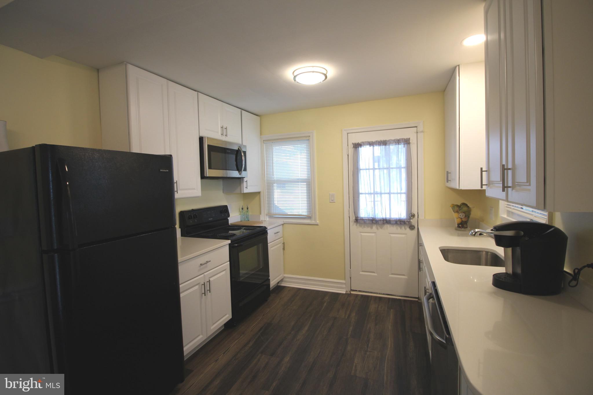 209 Champlain Avenue Wilmington, DE 19804 - Photo 6 of 26 a kitchen with a refrigerator a stove top oven a sink and dishwasher with wooden floor