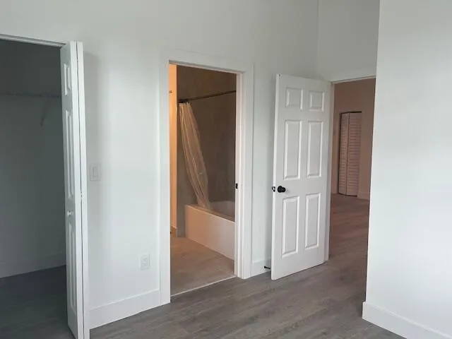 an empty room with wooden floor and a bathroom