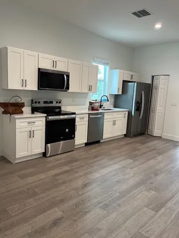 a large kitchen with cabinets stainless steel appliances and wooden floor
