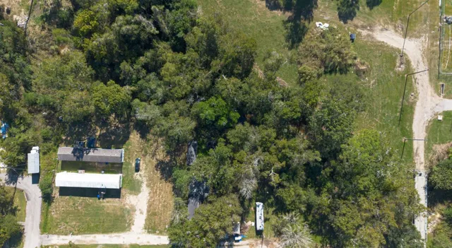 an aerial view of residential house with outdoor space and trees all around