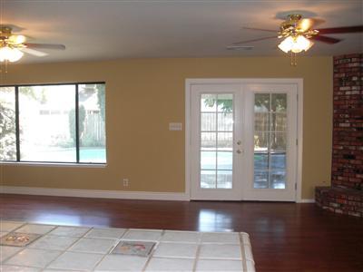 Living room, fresh paint, wood floor coverings, french doors leading to the patio, large window, 2 ceiling fans.