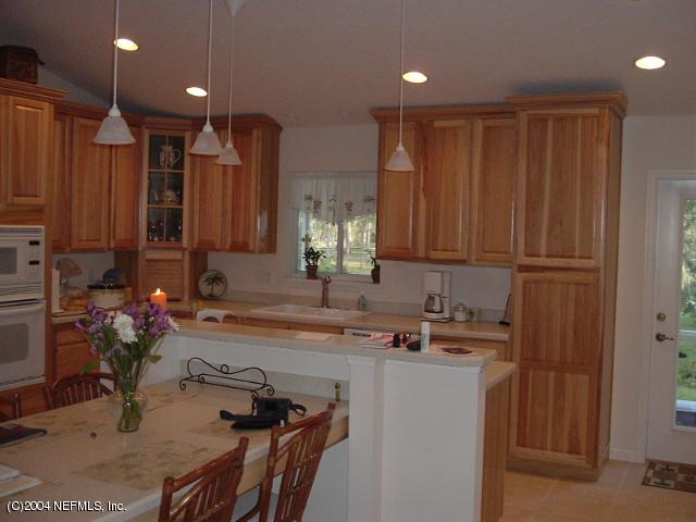 8435 Florence Cove Road St. Augustine, FL 32092 - Photo 10 of 20 a kitchen with kitchen island granite countertop a sink cabinets and wooden floor