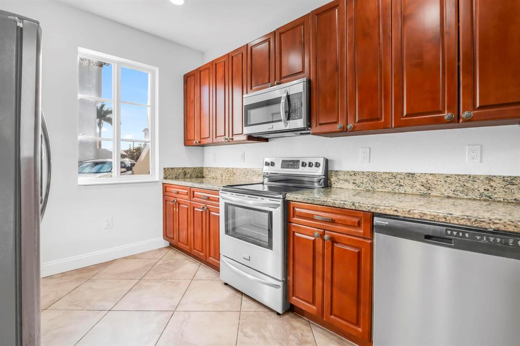 5030 Southwest 126th Avenue, Unit 203 Miramar, FL 33027 - Photo 7 of 41 a kitchen with stainless steel appliances granite countertop a stove a sink and a microwave