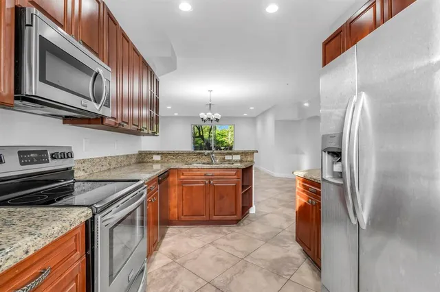 a kitchen with stainless steel appliances granite countertop a refrigerator a stove and a sink