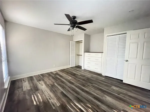 a view of empty room with wooden floor and fan
