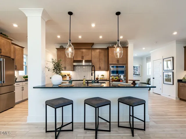 a kitchen with stainless steel appliances a stove a refrigerator a sink cabinets and wooden floor