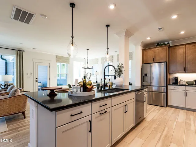 a kitchen with stainless steel appliances granite countertop a sink a stove a refrigerator and island with wooden floor