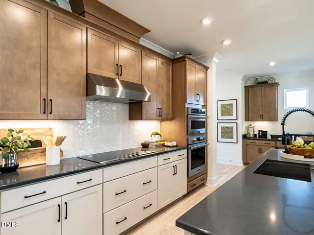 a large kitchen with stainless steel appliances a large counter top a stove and a wooden floors