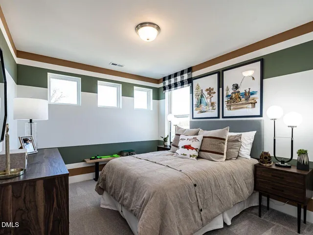 a bedroom with a large bed and a lamp on dresser