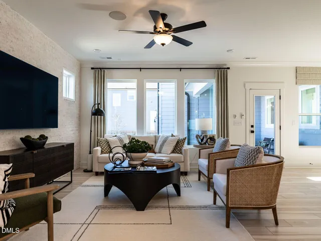 a living room with furniture a flat screen tv and a large window