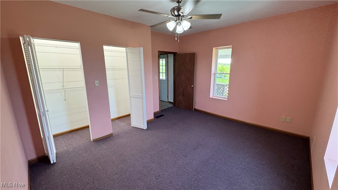 6255 Highland Ridge Road Lowell, OH 45744 - Photo 8 of 40 Unfurnished bedroom featuring multiple closets, dark carpet, baseboards, and ceiling fan