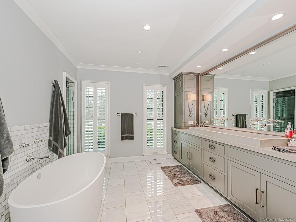 3429 Sharon Road Charlotte, NC 28211 - Photo 28 of 48 a spacious bathroom with a double vanity sink a large mirror and a bathtub
